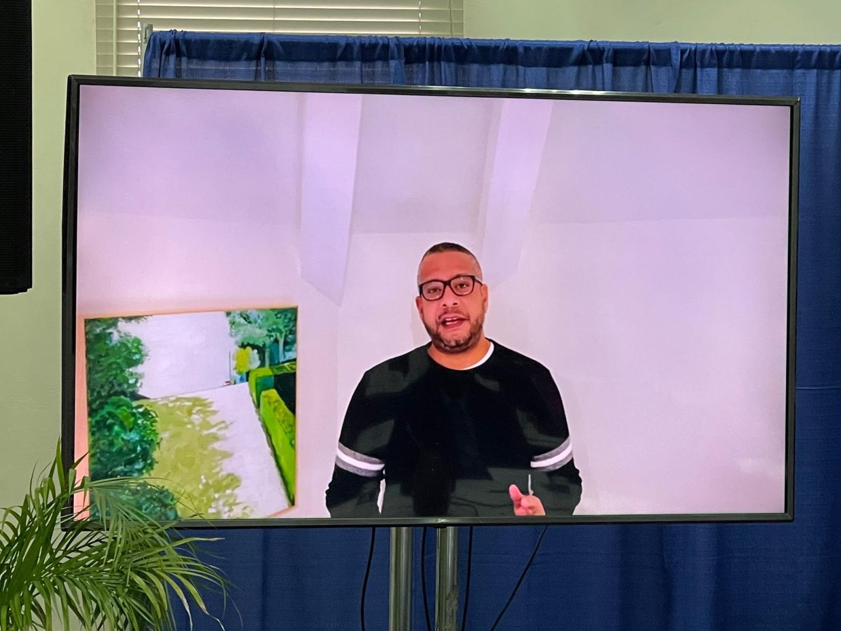 A man in glasses on a television screen talking