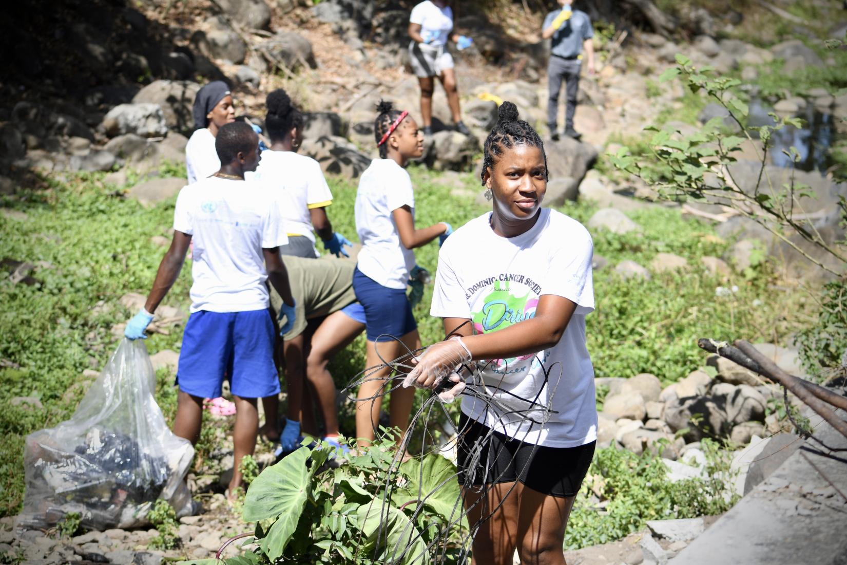 picture of a young girl holding metal wire in the midst of a river clean up