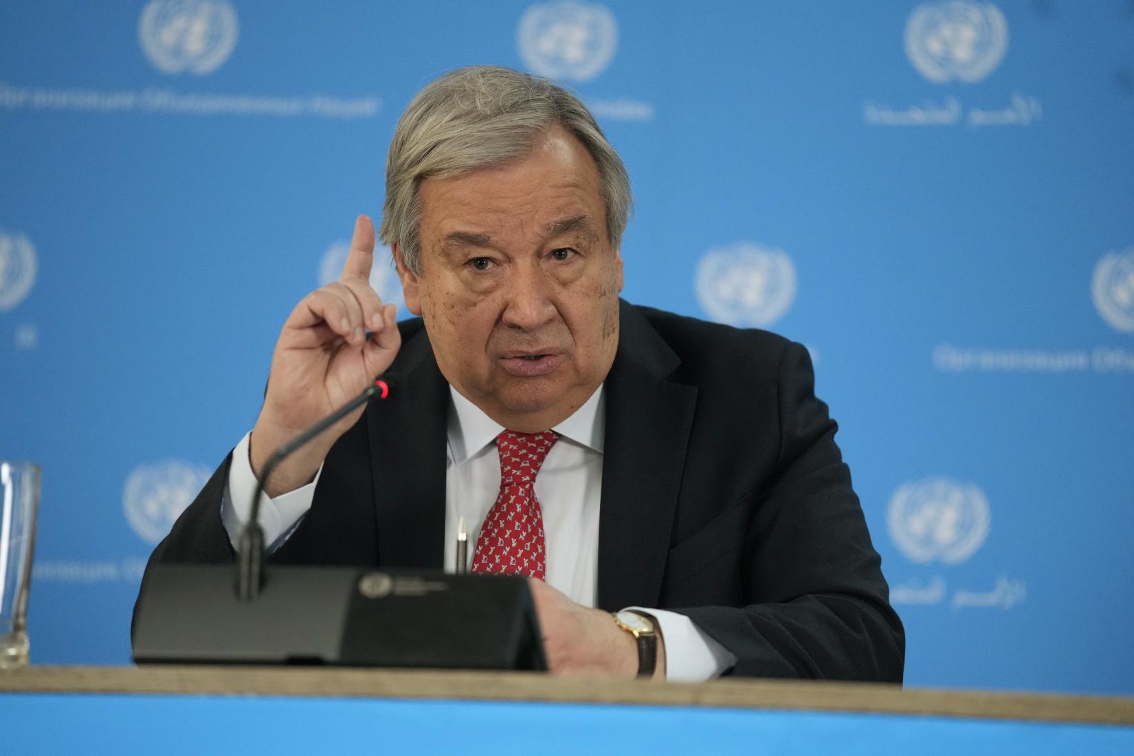 Man at podium speaks to an audience with banners in the background