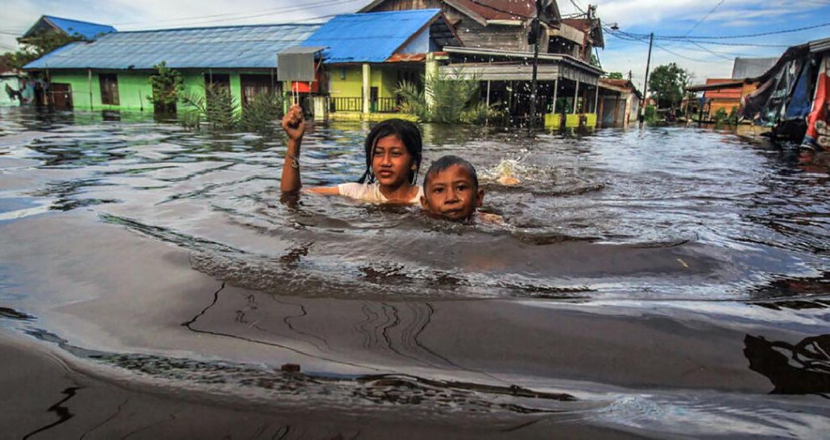 Photo of children trying to keep their heads above high flood water