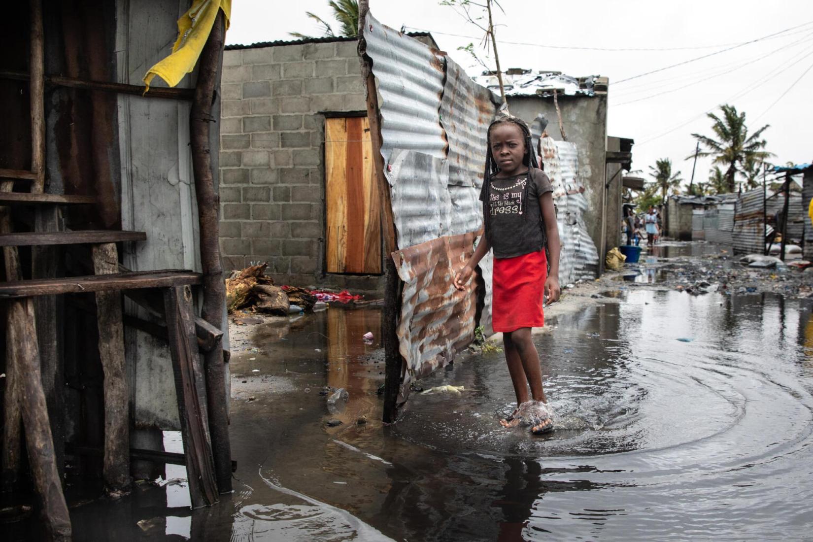 girl stands in a flooded area, with grey skies and post storm conditions