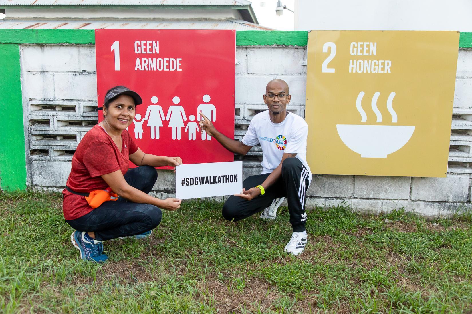 SDG Walkathon participants showcase the event's hashtag while posing in front of an SDG display along the route