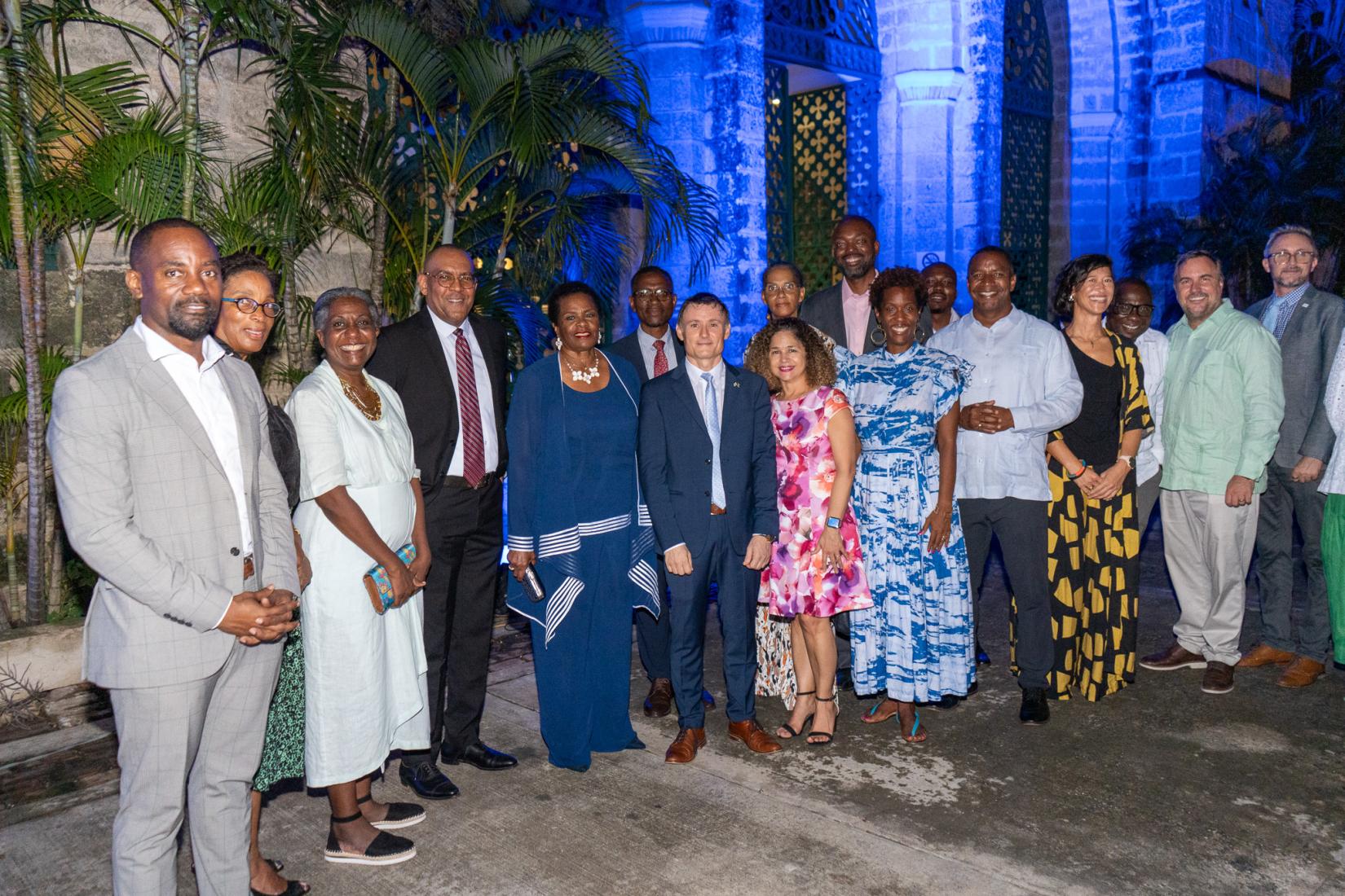 group of men and women standing together with a parliament building in the background bathed inblue