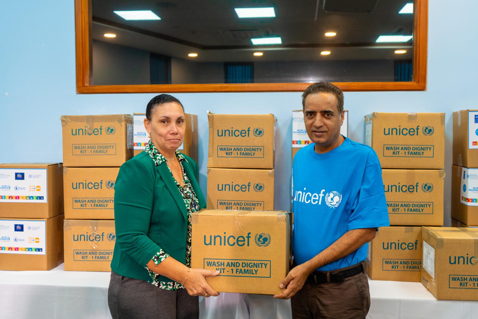 man and woman stand holding a UNICEF branded Dignity Kit for a photo op