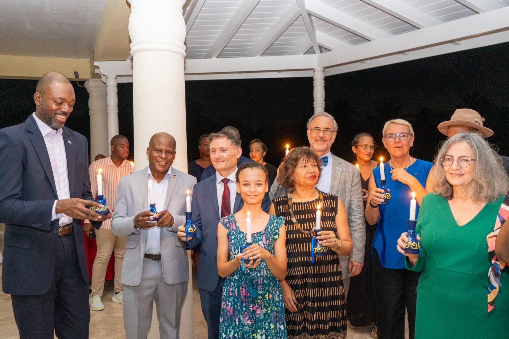 group of people stand together holding lit candles shoulder to shoulder