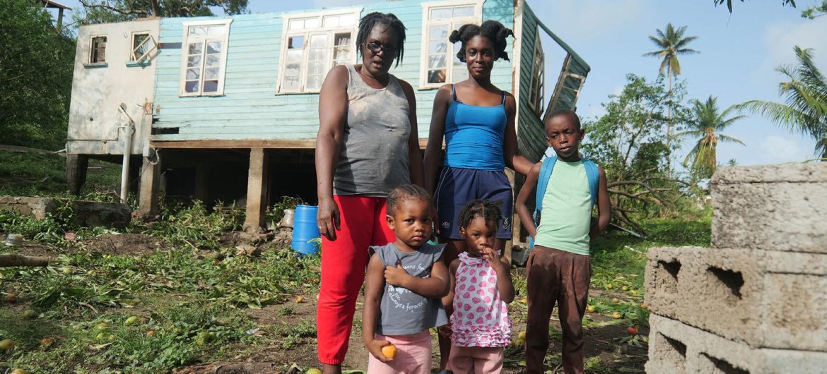 Family standing outside their home destroyed by Hurricane Beryl in Grenada