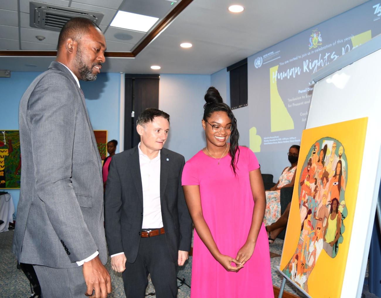Minister of Labour, Social Security and the Third Sector, the Honourable Colin Jordan, UN Resident Coordinator for Barbados and the Eastern Caribbean, Didier Trebucq, and Painter, Alisha Smith, discuss her specially commissioned artwork during the 2022 Human Rights Day Event.