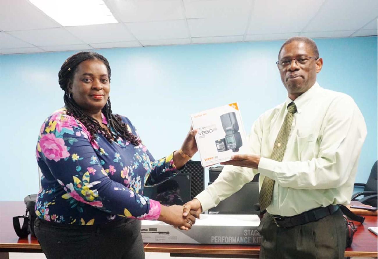 Photo of a man and woman standing and presenting a camera lens still in the box