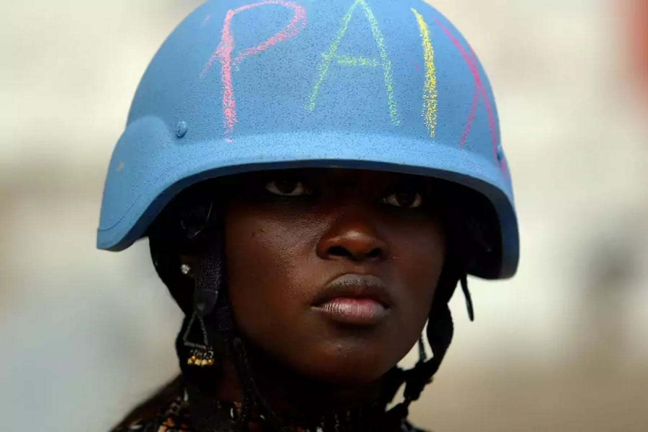 A U.N. Peacekeeper wears a helmet with the word "peace" written on it in Martissant, Haiti.