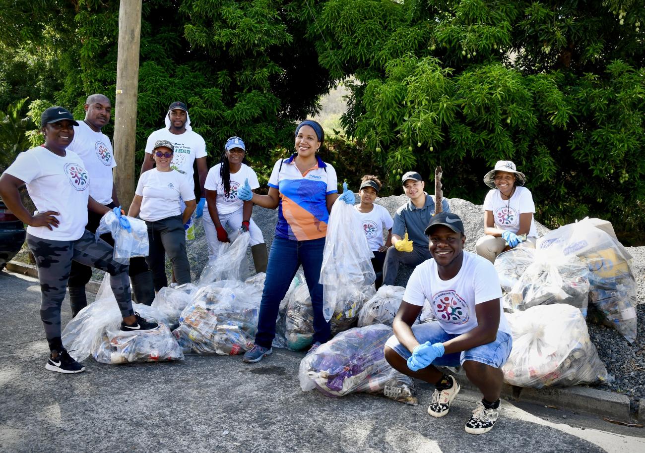 group of people stand smiling with bags of plastic waste collected from a river