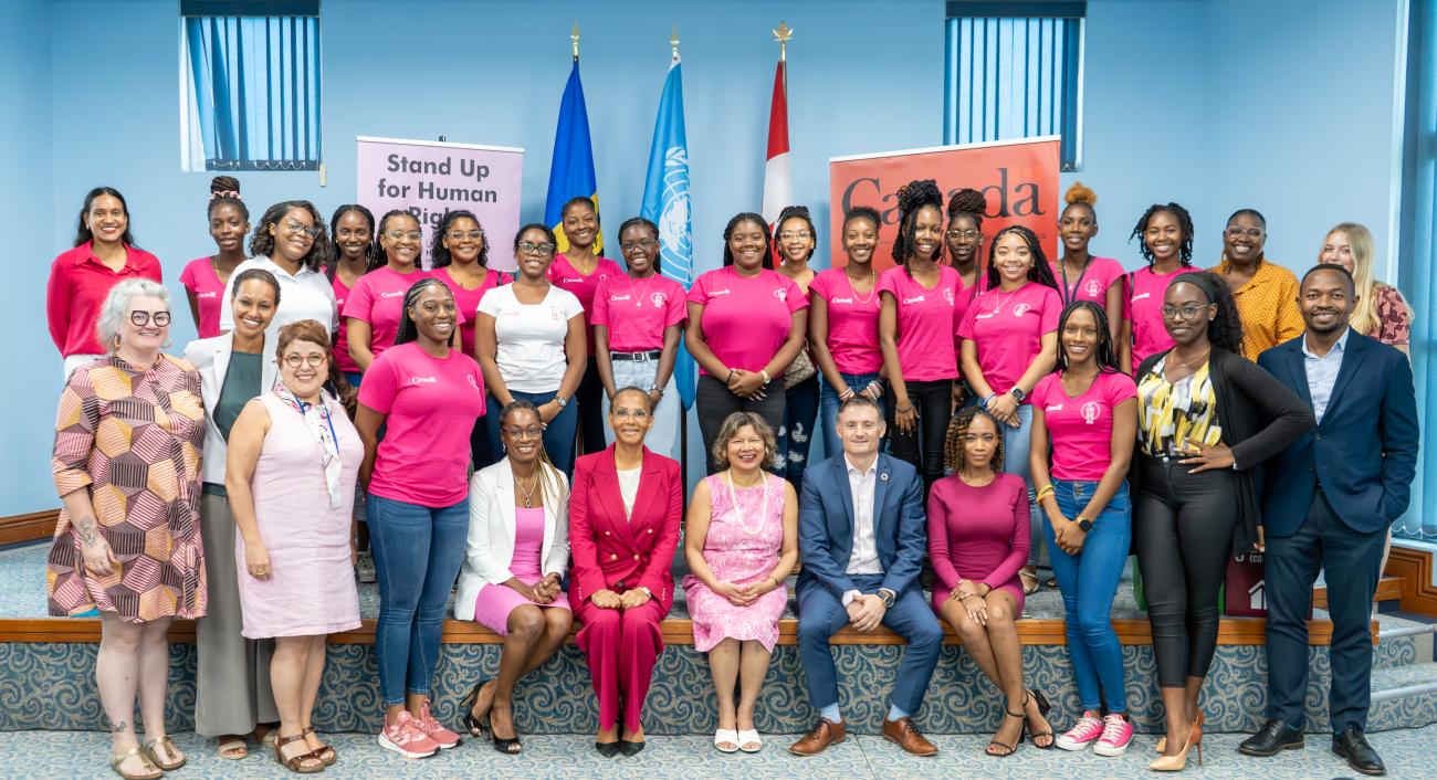 A group of young women from Pink Parliament Barbados pose with UN Resident Coordinator Didier Trebucq, High Commissioner of Canada H.E. Lilian Chatterjee, and other officials from the UN and the High Commission of Canada.