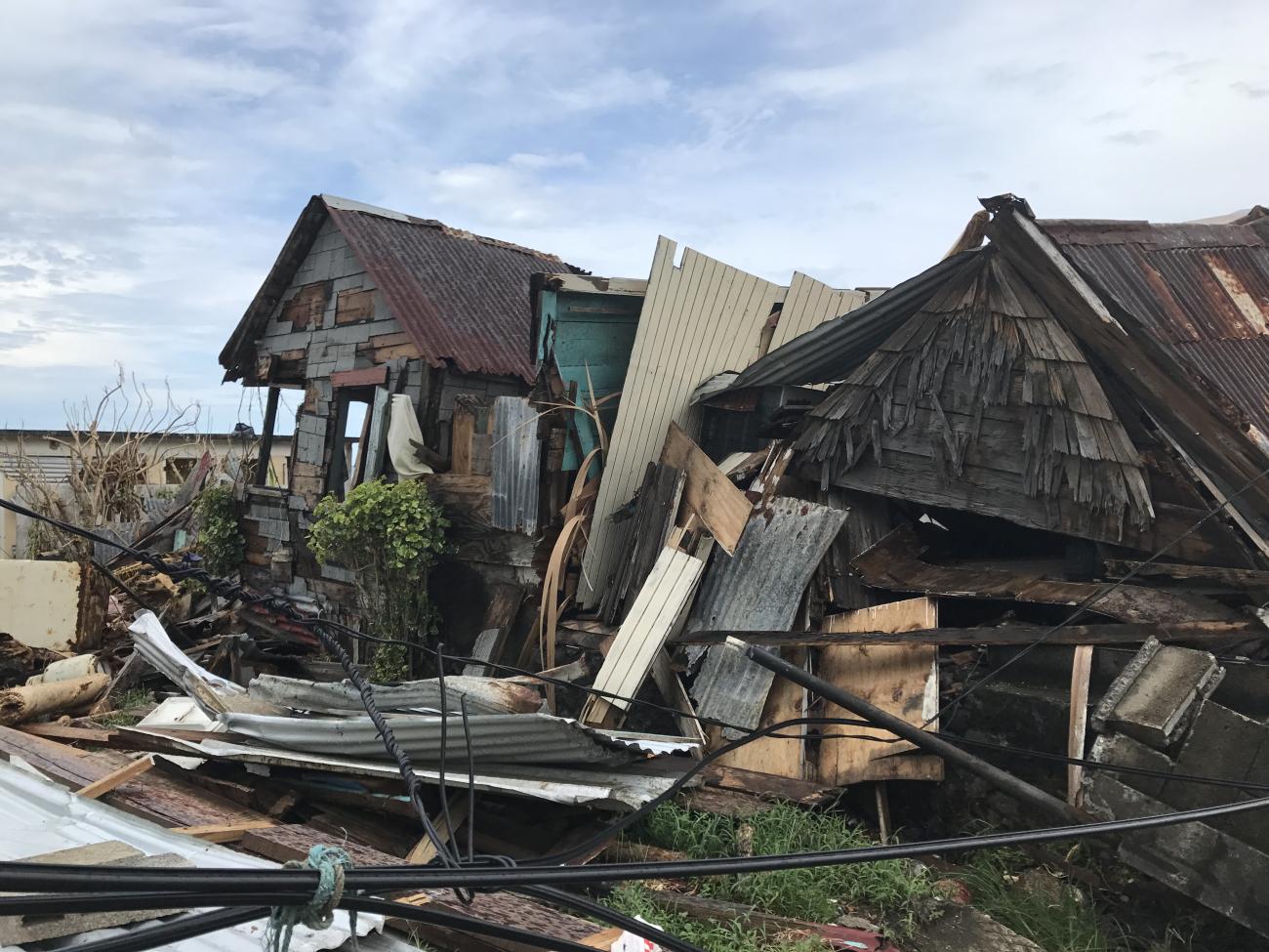 destroyed wooden house, loose materials, and wires from natural disaster