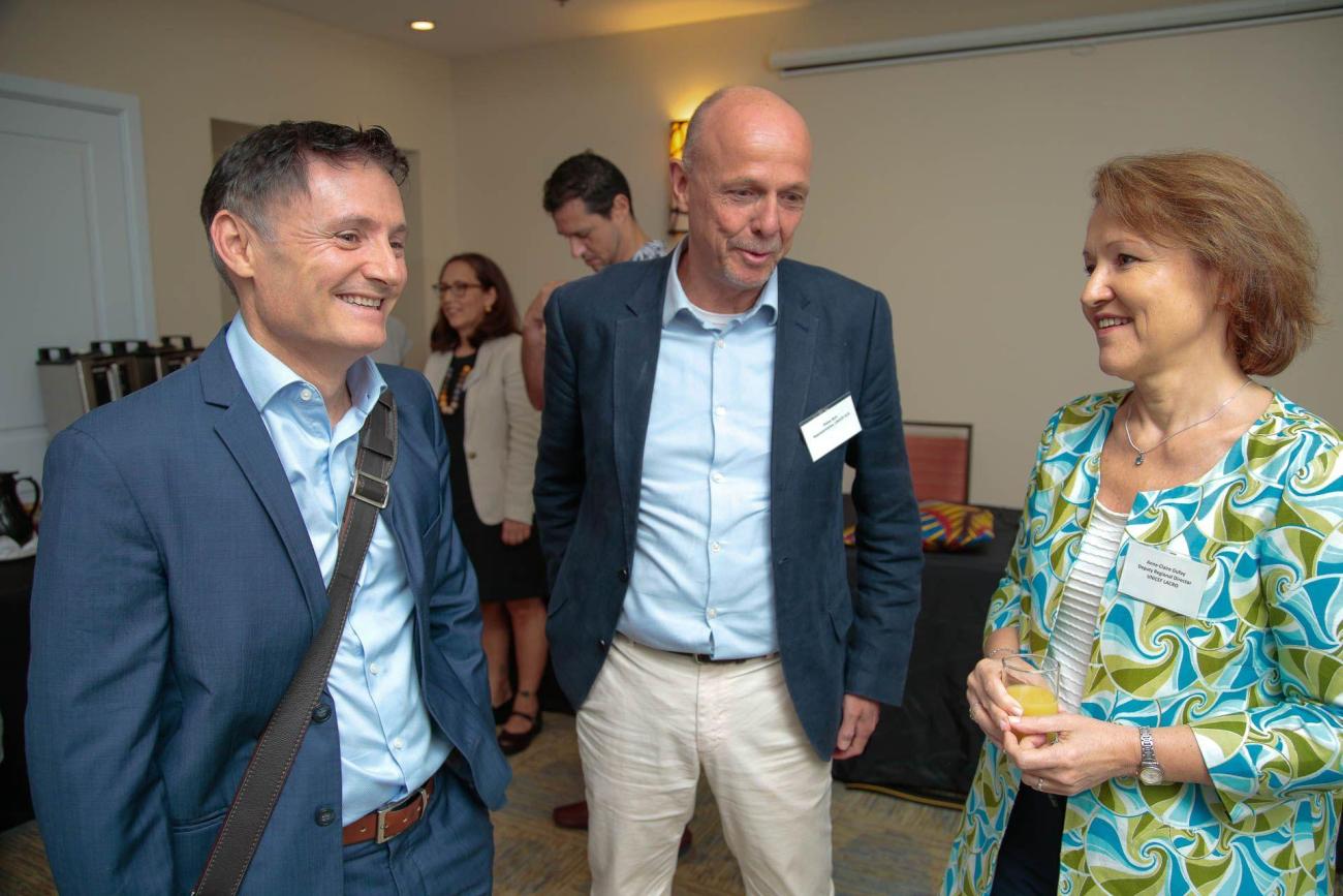 two men in suits share a light moment with a lady to their right in professional wear