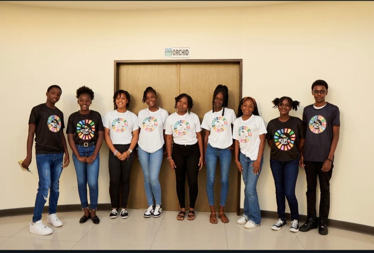 young people in black and white t shirts with SDG wheels on the front stand together for a photo