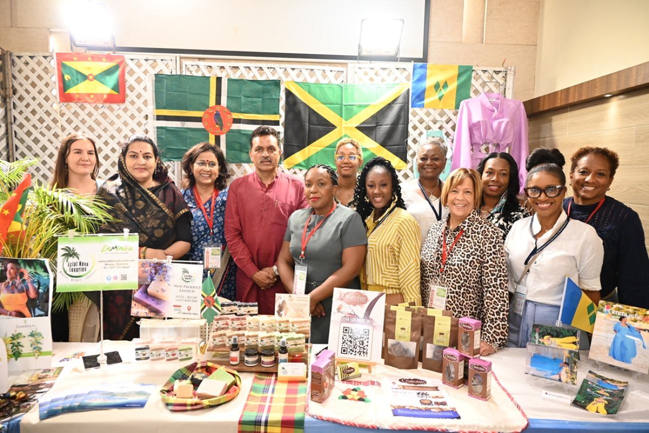 UN Women officers and Caribbean women entrepreneurs stand together smiling at the MAWE inauguration
