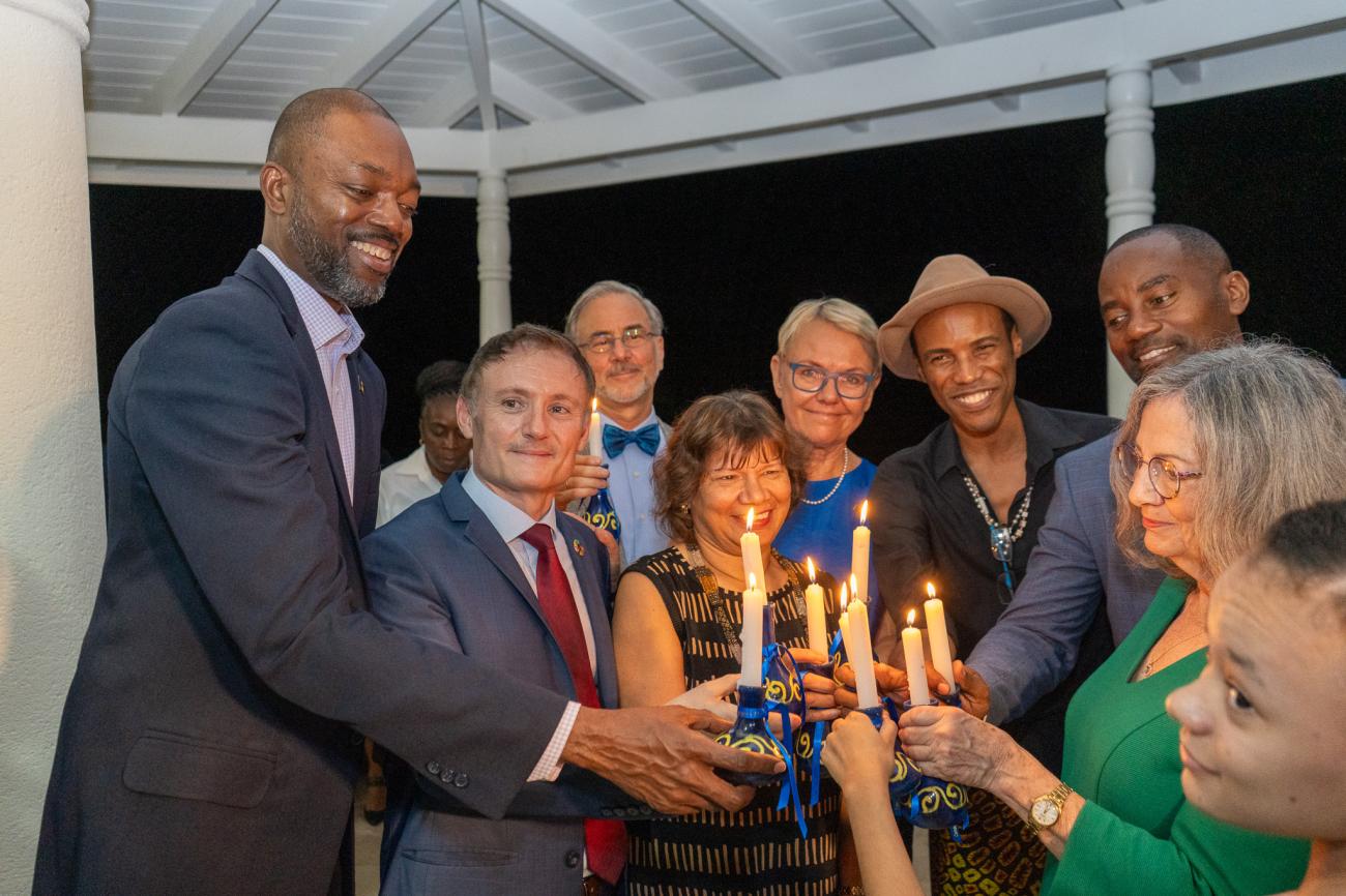 group of people form a circle placing lit candles in the middle for a photo op