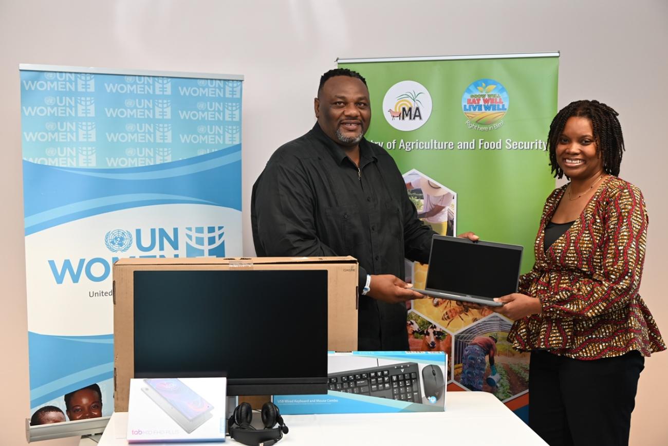 A woman presenting a computer to a man in front of banners