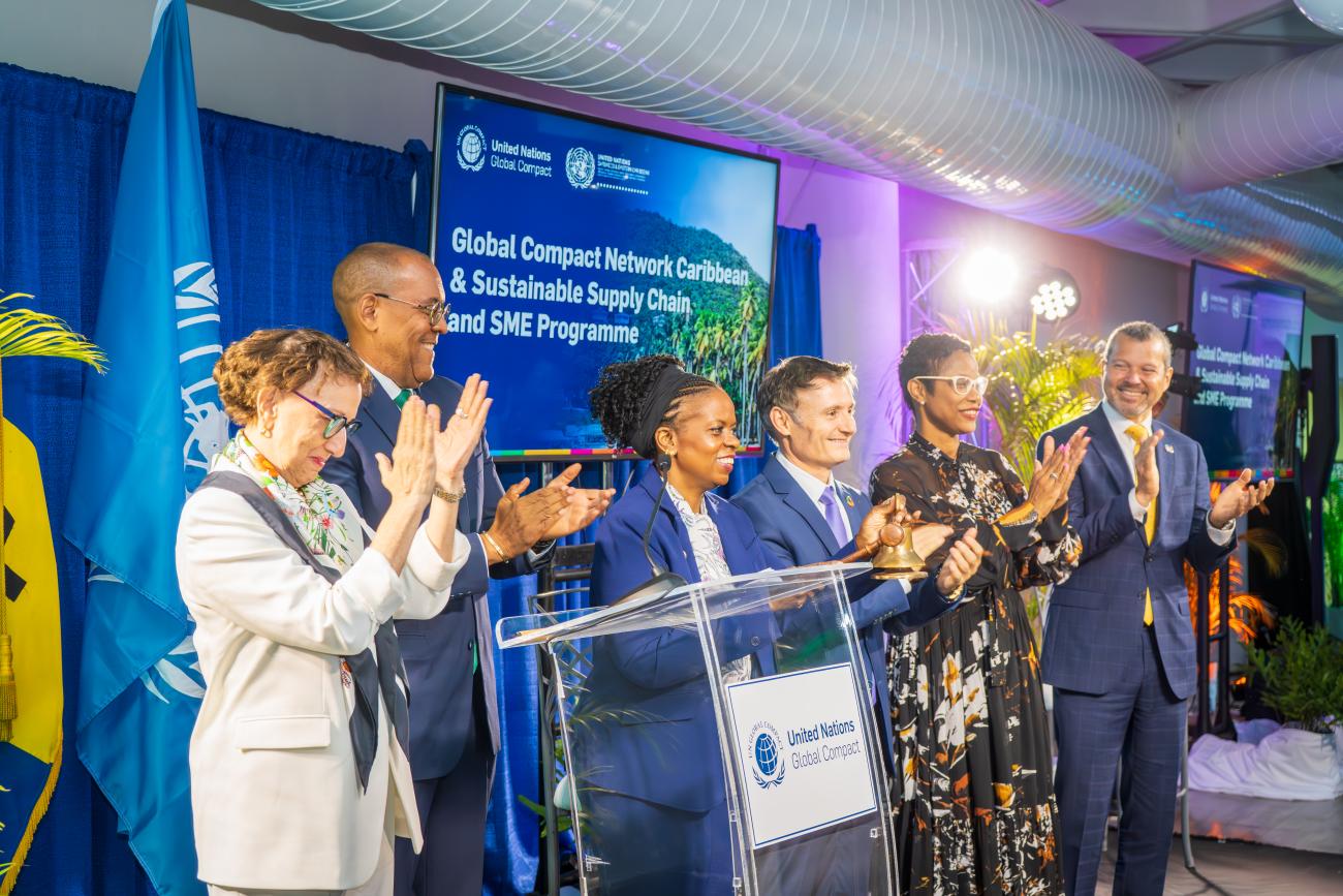 A group of people stand together applauding in front of a podium