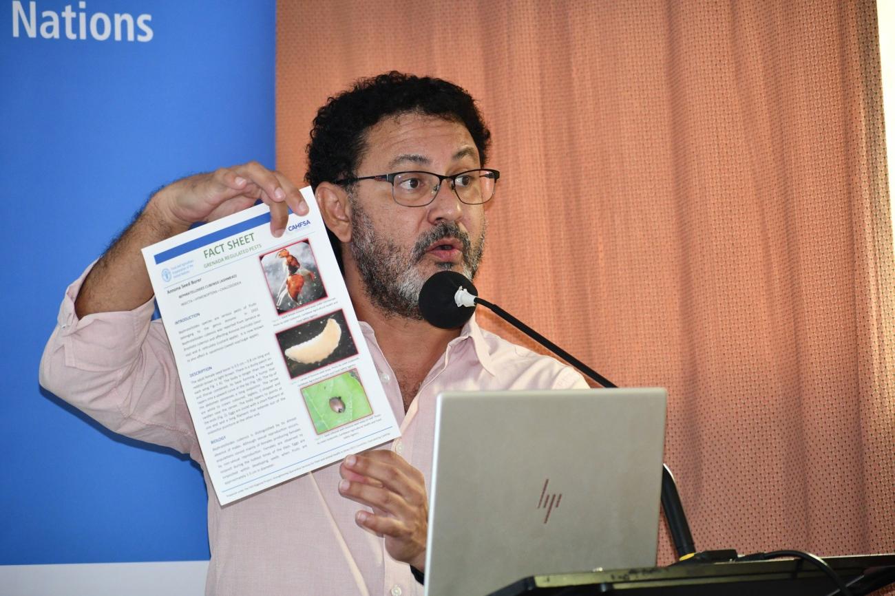 A man holding a paper in front of a microphone and an audience