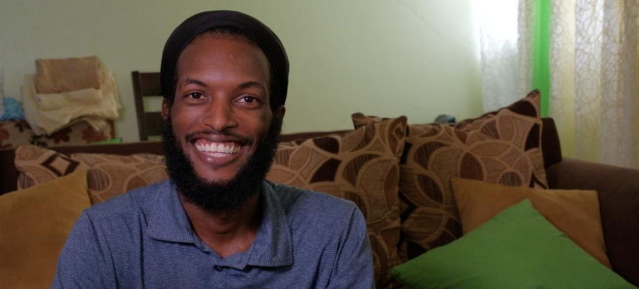 A bearded young man smiling widely at  the camera