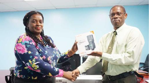 Photo of a man and woman standing and presenting a camera lens still in the box