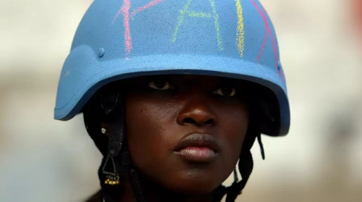 A U.N. Peacekeeper wears a helmet with the word "peace" written on it in Martissant, Haiti.