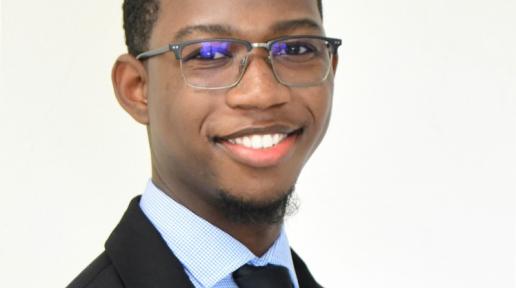 headshot image of a young man in a tie smiling 