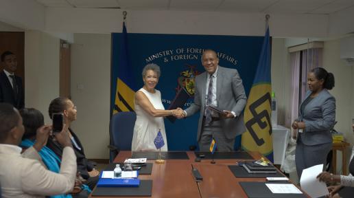 Man and woman exchange folder in a boardroom to a small gathering