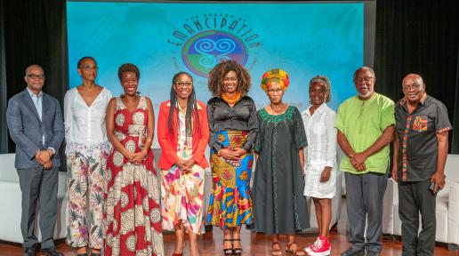 group photo of participants standing on stage smiling with a banner in the background