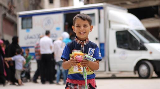 A child holds medicine he received from health workers at a mobile health clinic in a neighbourhood of eastern Aleppo, Syria.