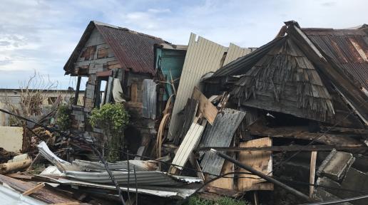 destroyed wooden house, loose materials, and wires from natural disaster