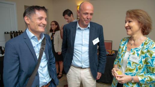 two men in suits share a light moment with a lady to their right in professional wear