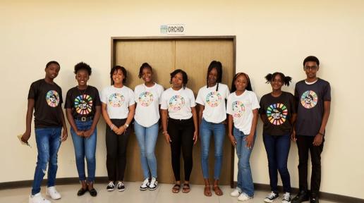 young people in black and white t shirts with SDG wheels on the front stand together for a photo