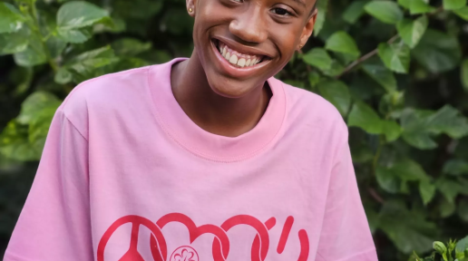 young girl gives a bright smile in a pink shirt in a garden area