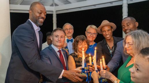 group of people form a circle placing lit candles in the middle for a photo op