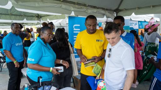 two men stand at an exhibition table observing the materials on display