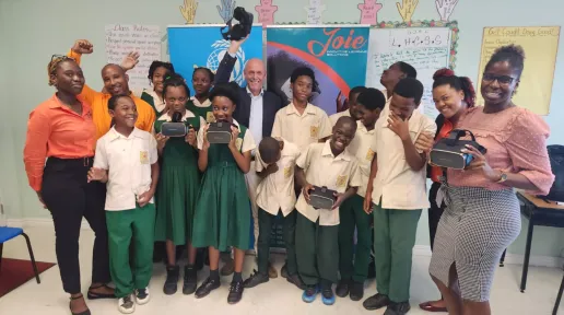 A group of students and teachers in uniform holding VR headseats posing for a photo