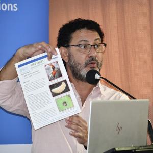 A man holding a paper in front of a microphone and an audience